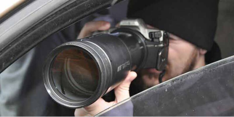photo of a man with a camera, taking a photo through the open window of a car